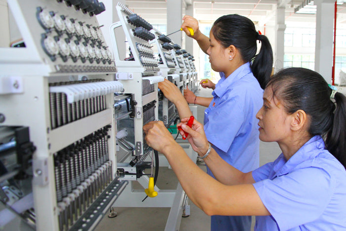 Two women working on a machine in an industrial setting