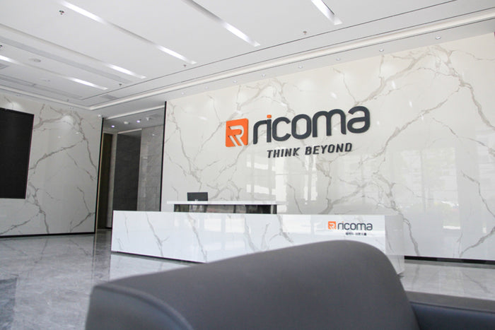 Modern office interior with 'ricoma' logo on a marble wall.